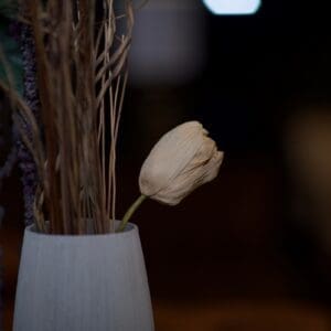 A white vase with some flowers in it