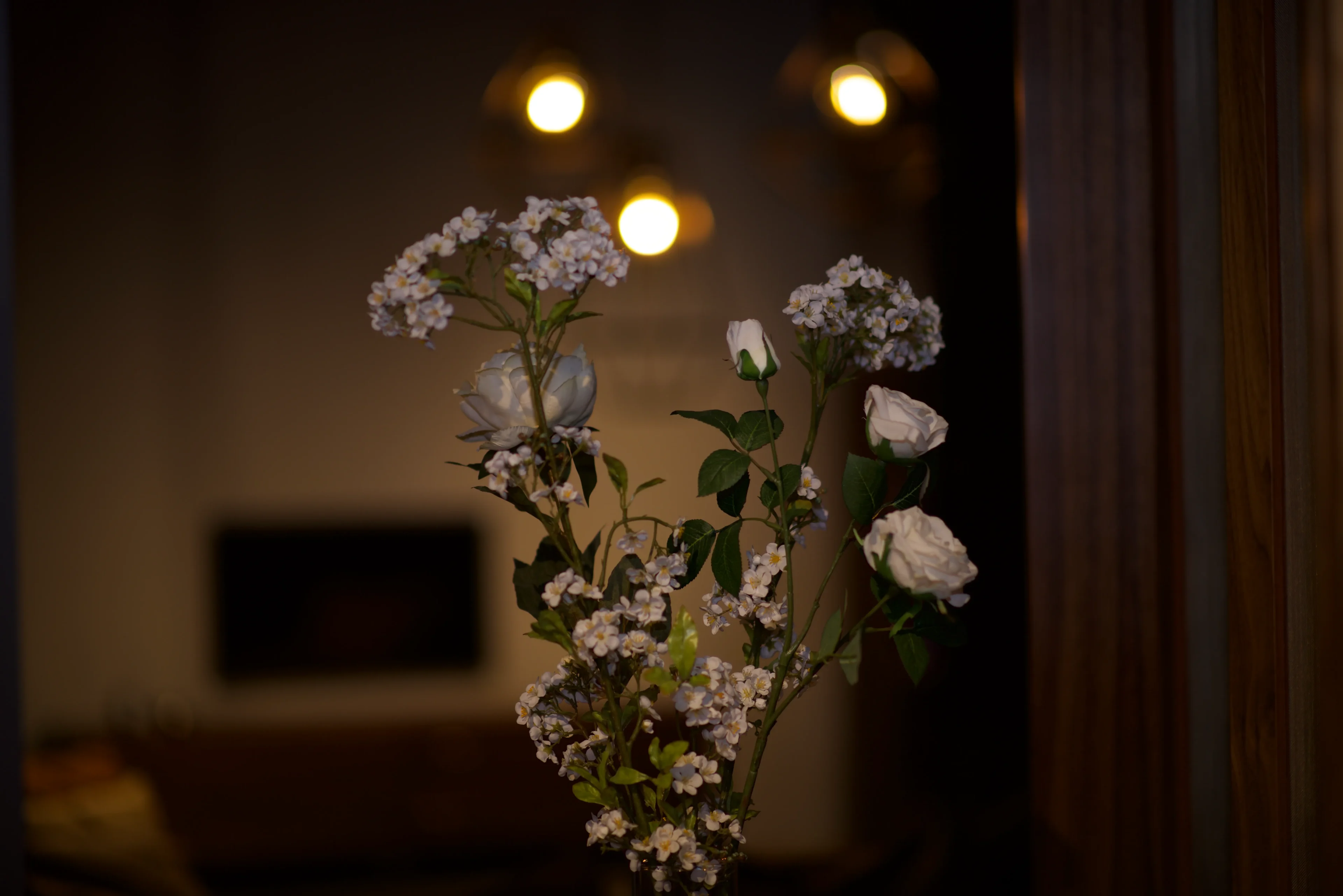 A vase of flowers in front of lights.