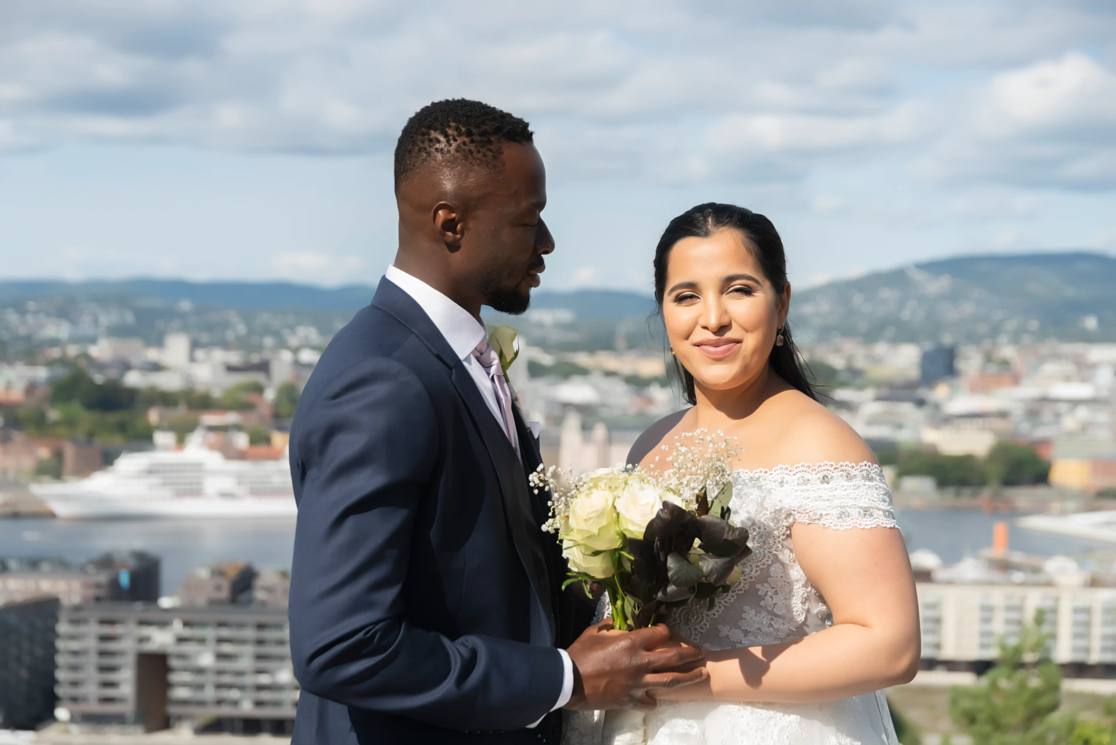 A man and woman holding flowers in front of a city.