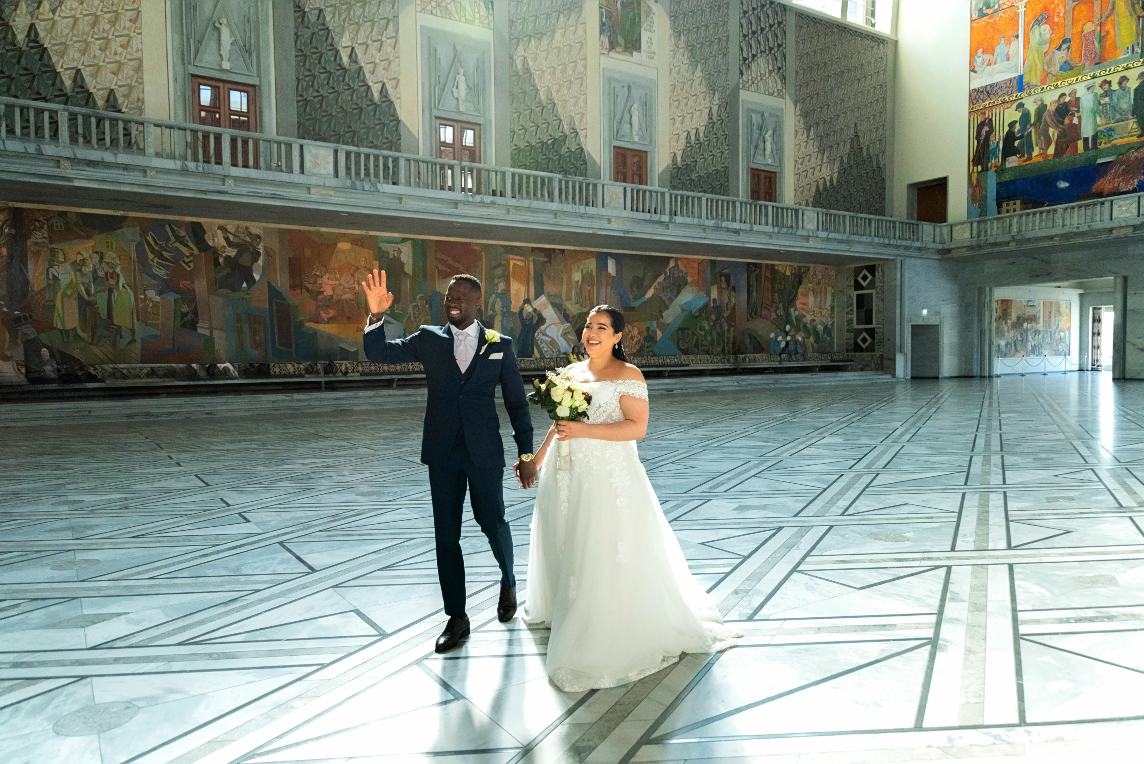 A man and woman walking in the middle of an indoor area.